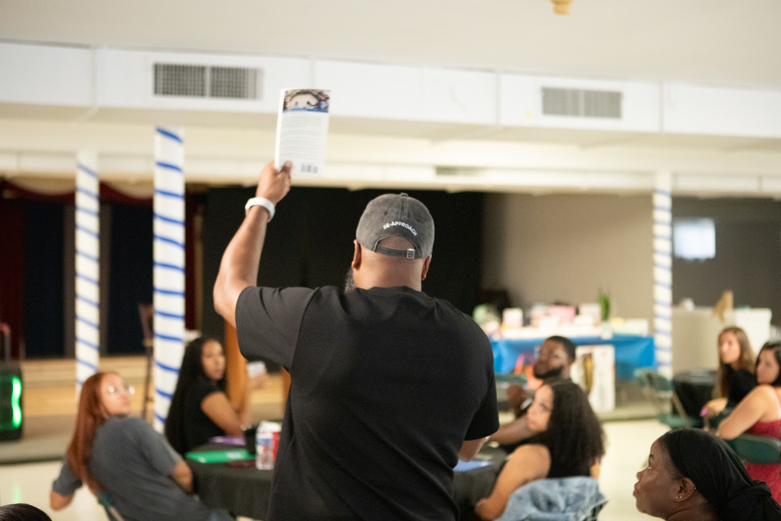 Neil Ray holding up a card as educators at tables look on