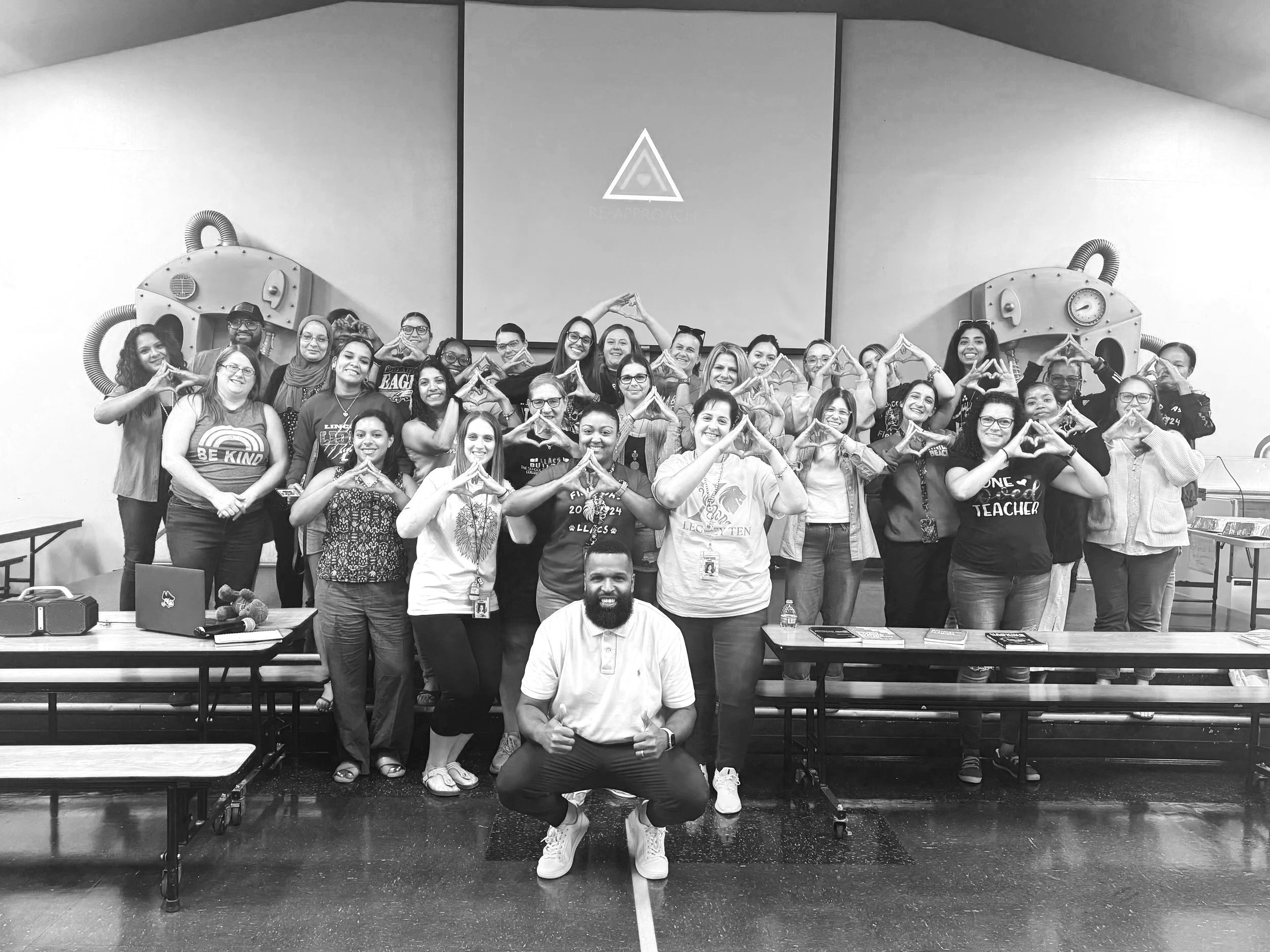 Room full of educators making a triangle hand sign together