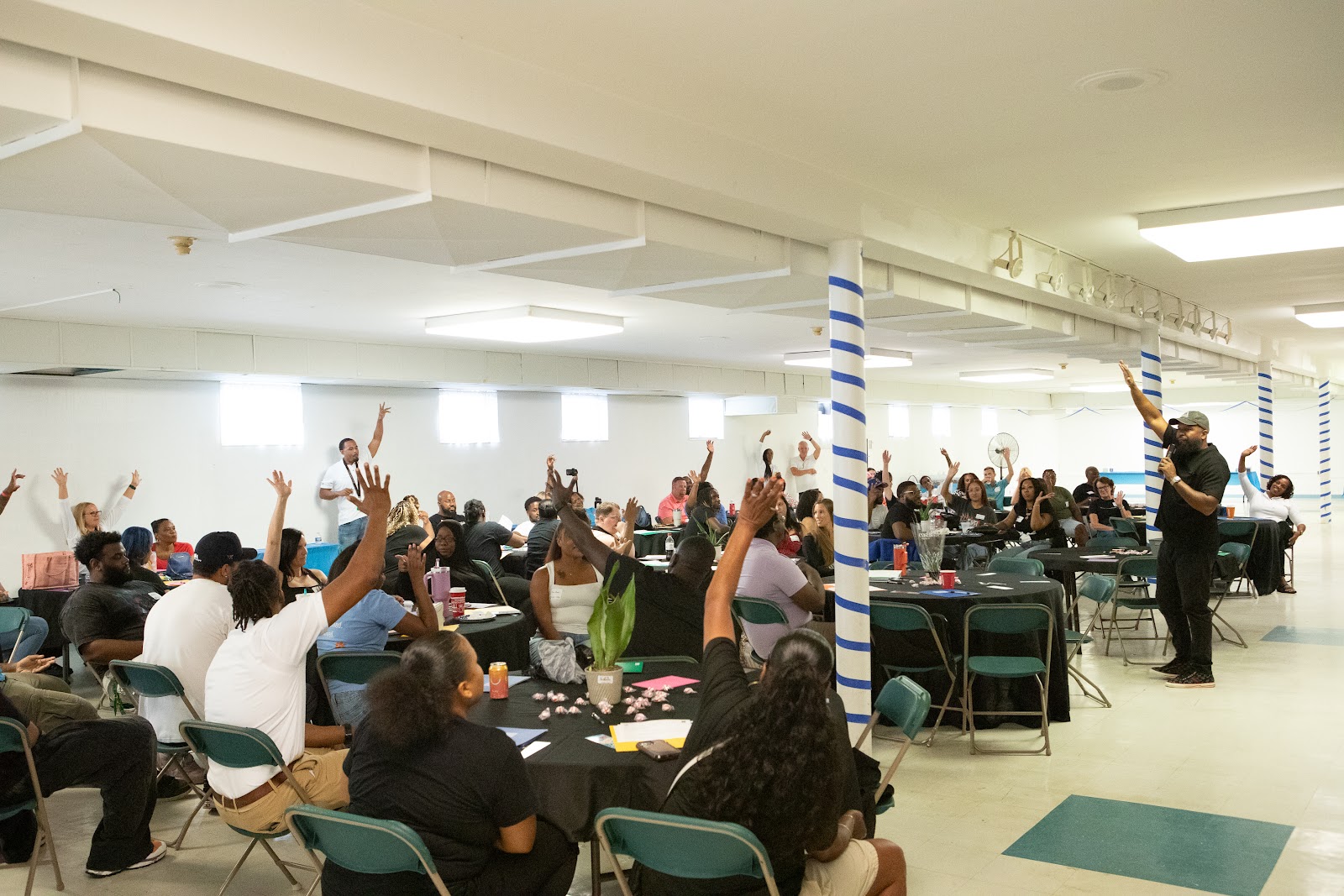 A room of educators raising their hands during a Re-Approach session