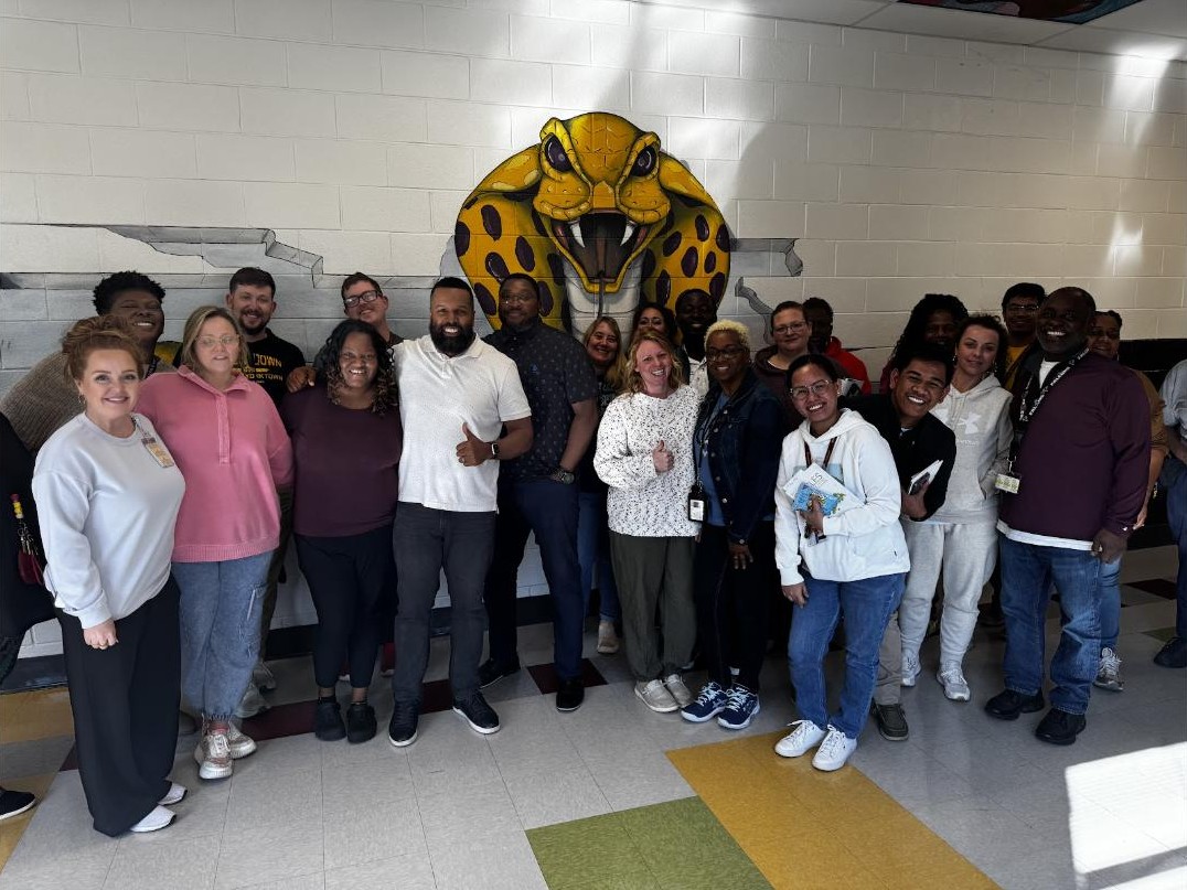 Neil Ray with a school team in front of their mascot mural