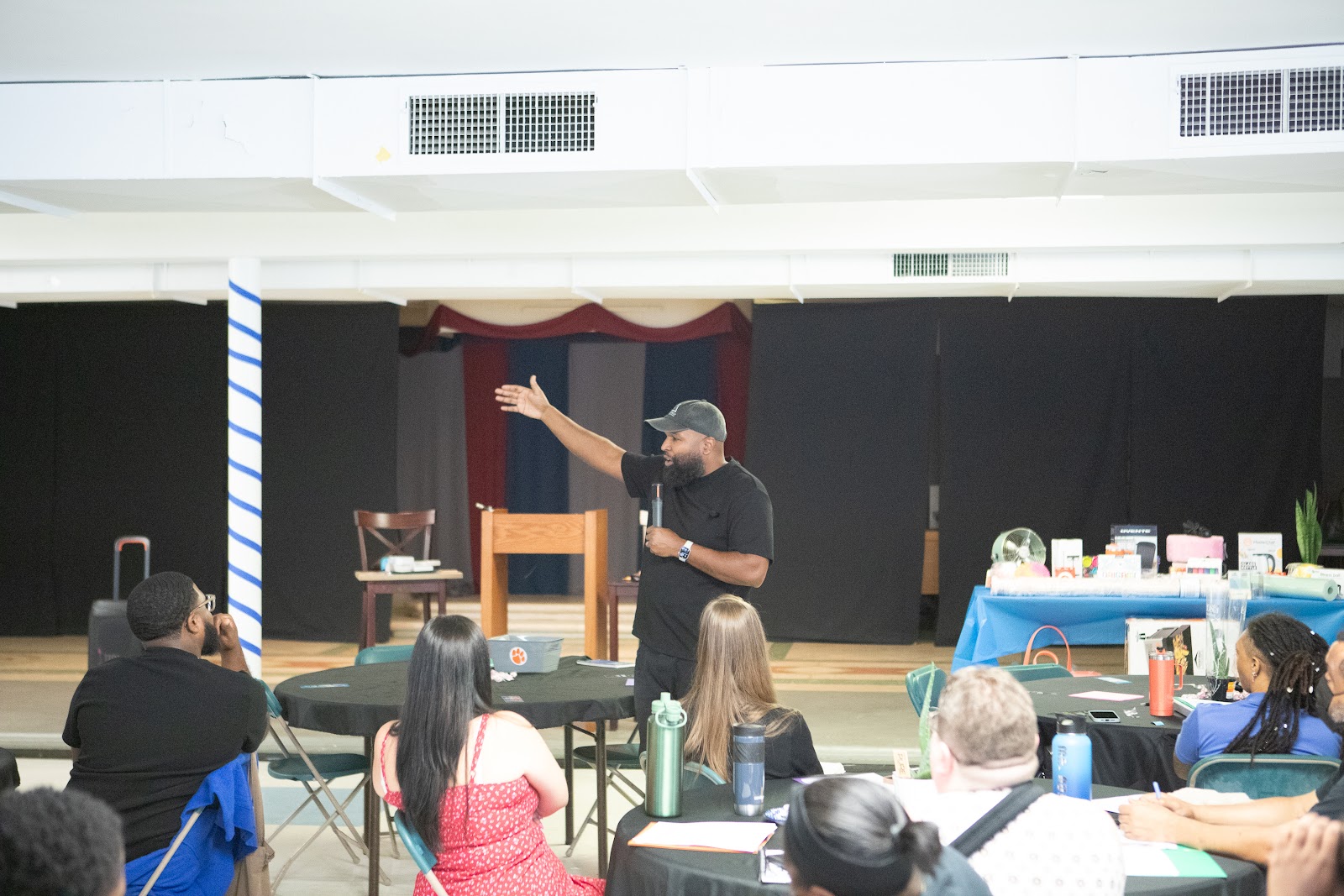 Neil Ray gesturing toward a room of educators at tables