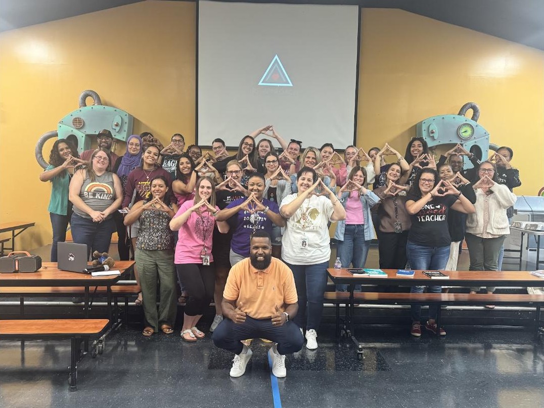 School staff making the Re-Approach triangle sign with Neil Ray in front