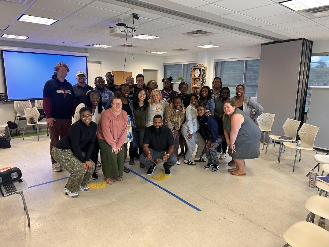 Neil Ray crouching in front of a large group of staff after a training