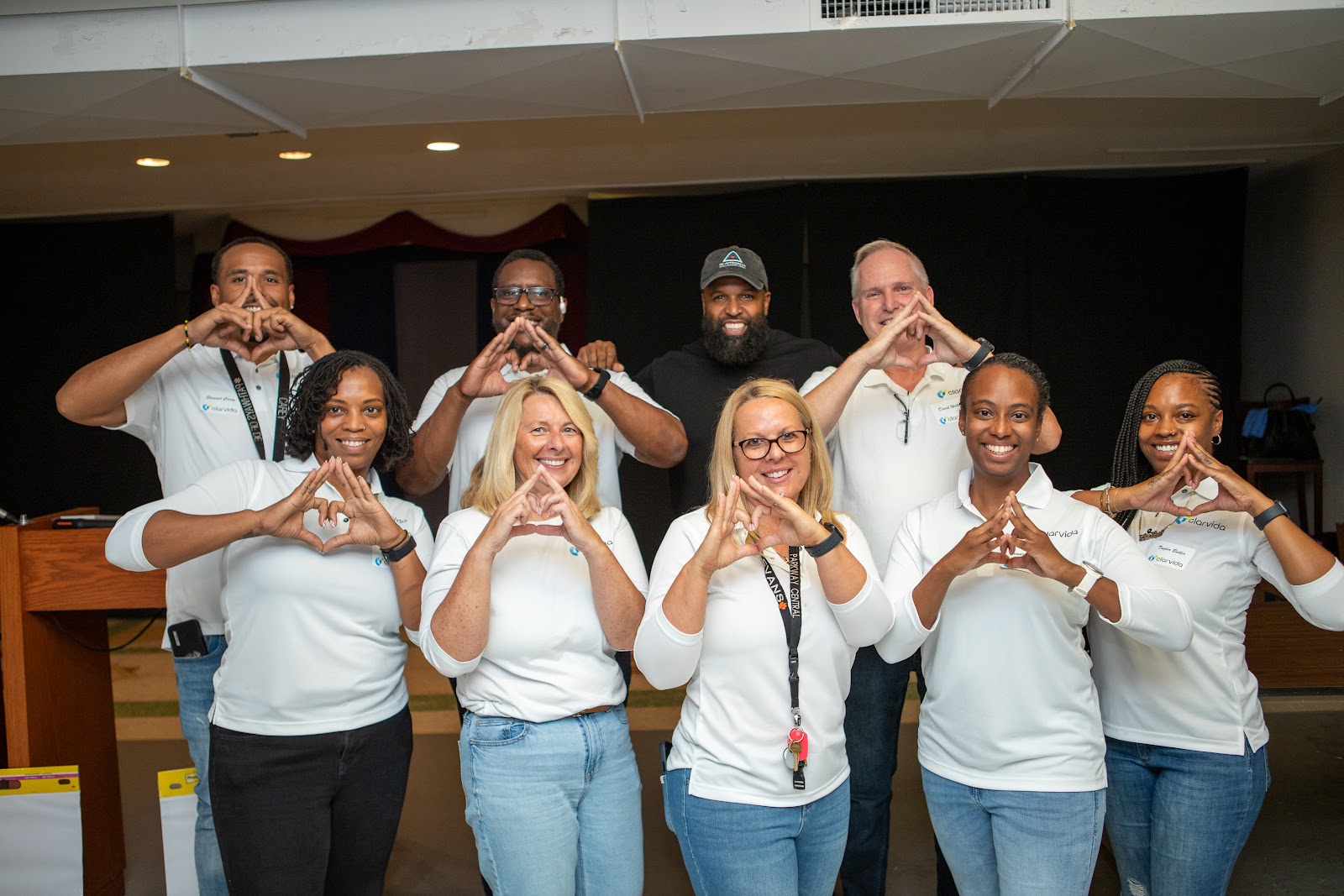 A leadership team making the Re-Approach triangle sign with Neil Ray